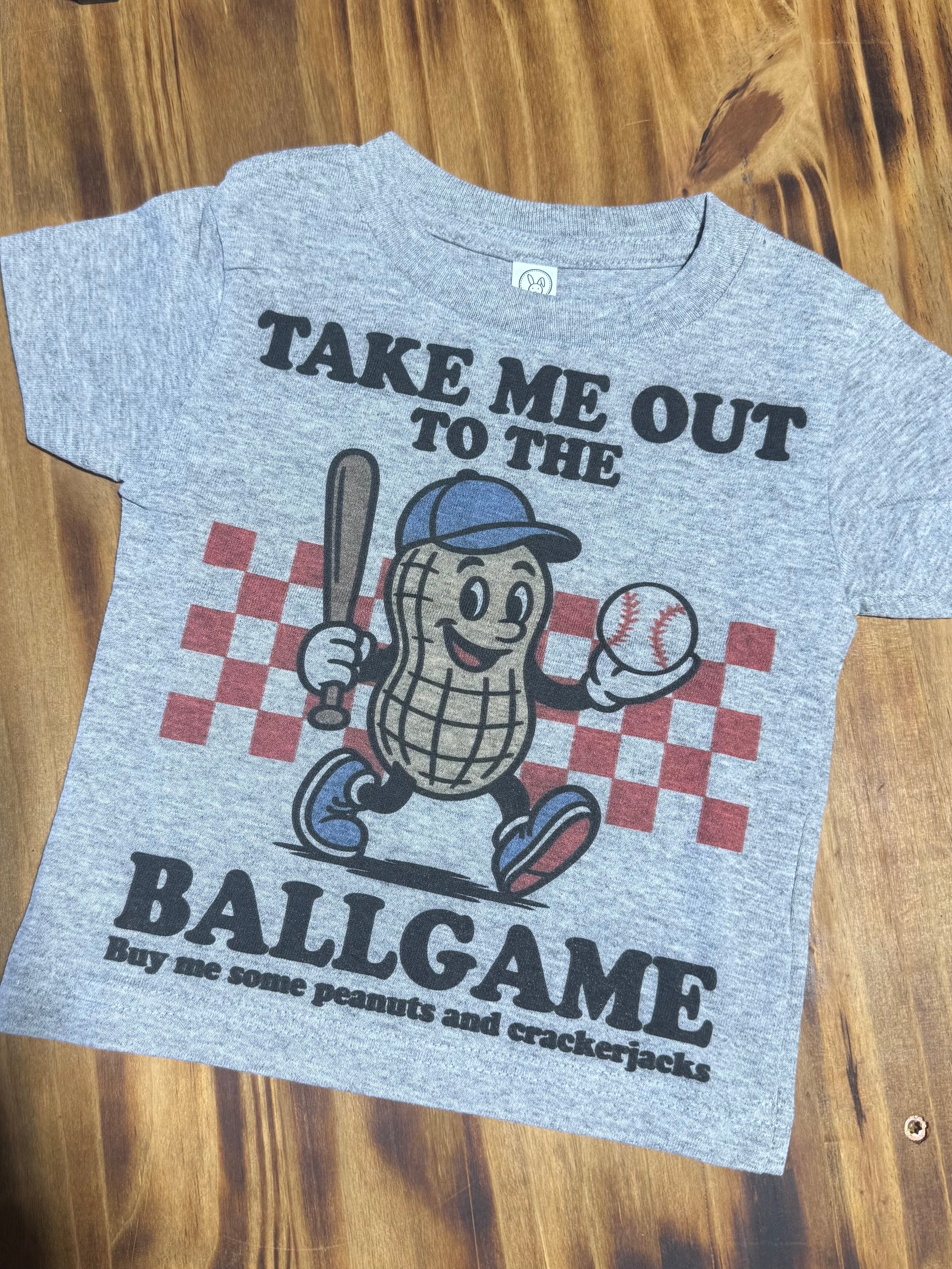 A heather gray short-sleeve t-shirt with a baseball-themed graphic featuring a peanut character holding a bat and baseball, with the text 'TAKE ME OUT TO THE BALLGAME' and 'Buy me some peanuts and crackerjacks'